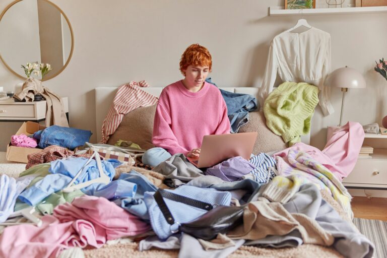 Indoor shot of serious woman with ginger hair wears pink jumper keyboards on laptop computer poses